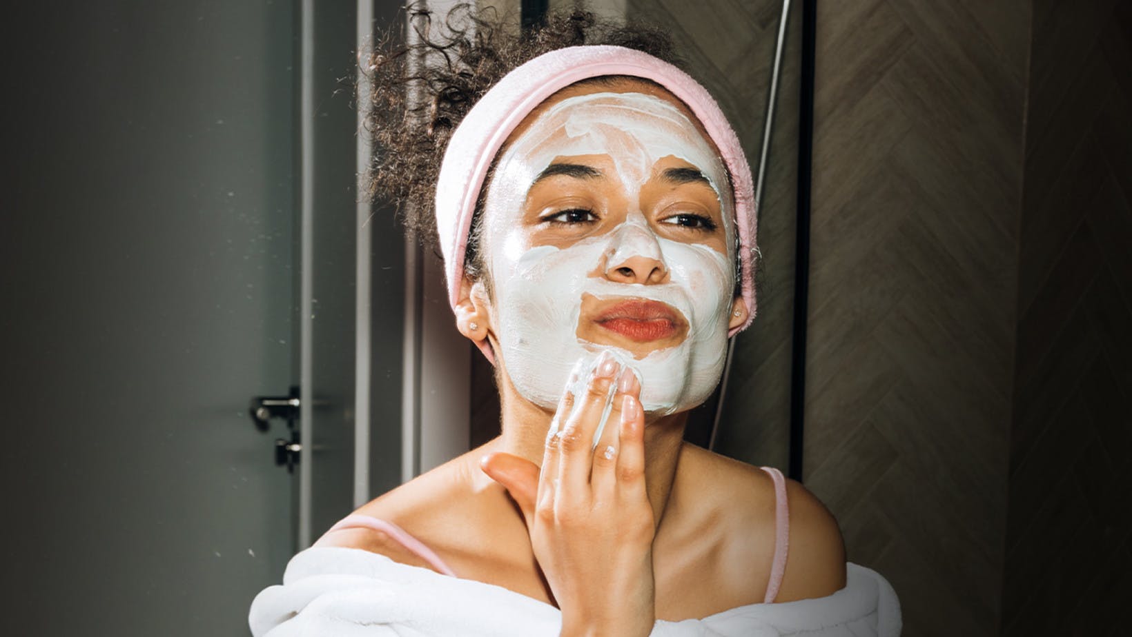 Female college student practicing self-care by putting on a facial mask
