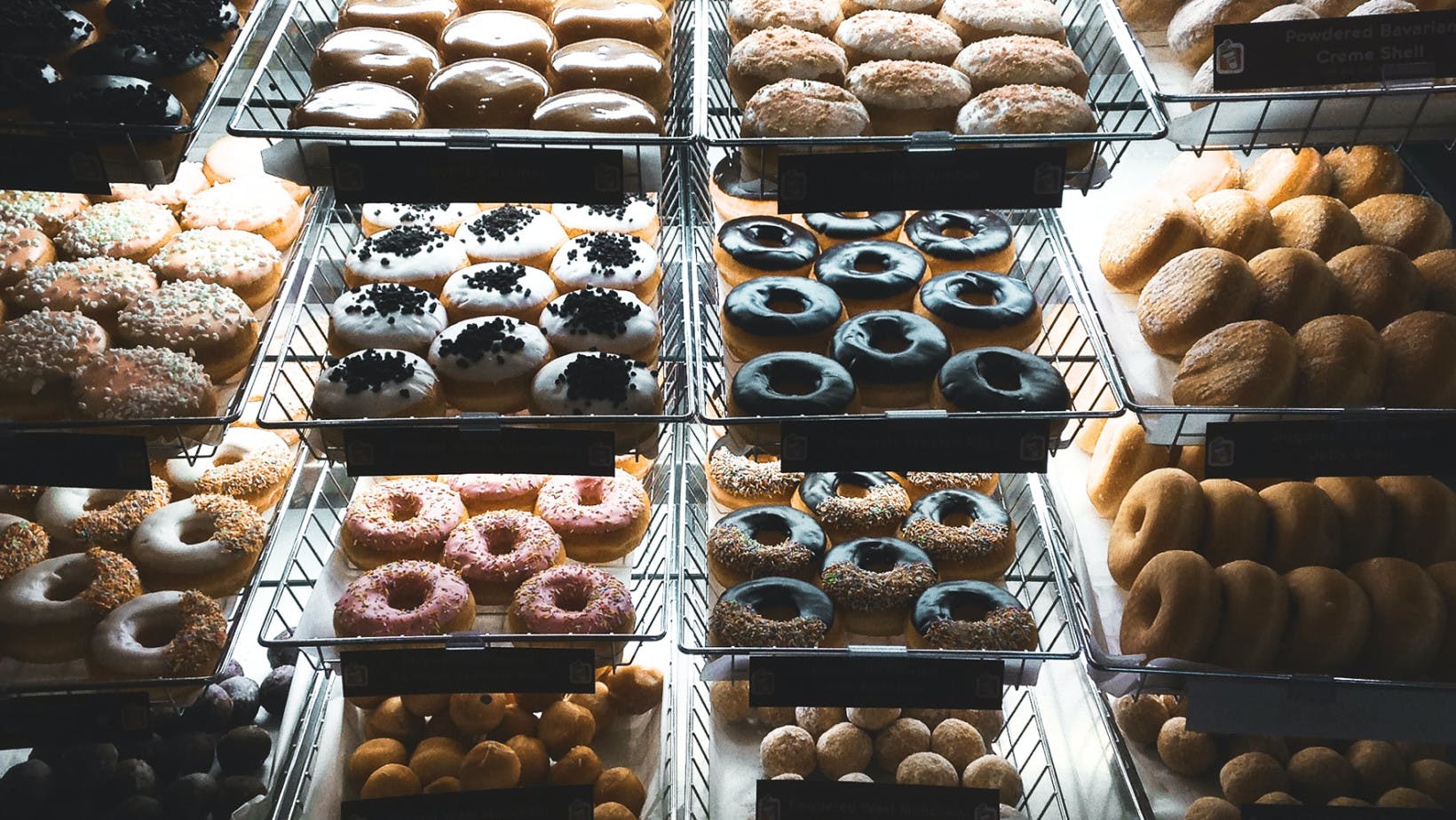 Trays of donuts on shelf in a bakery. 