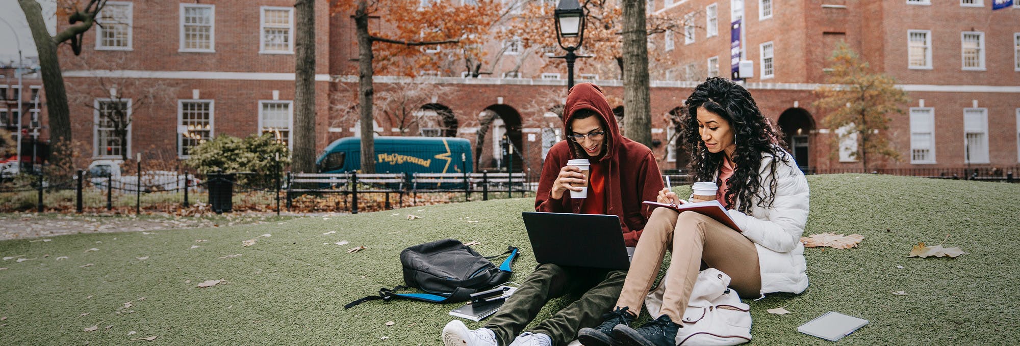 Two freshmen college students sitting outside on campus grounds