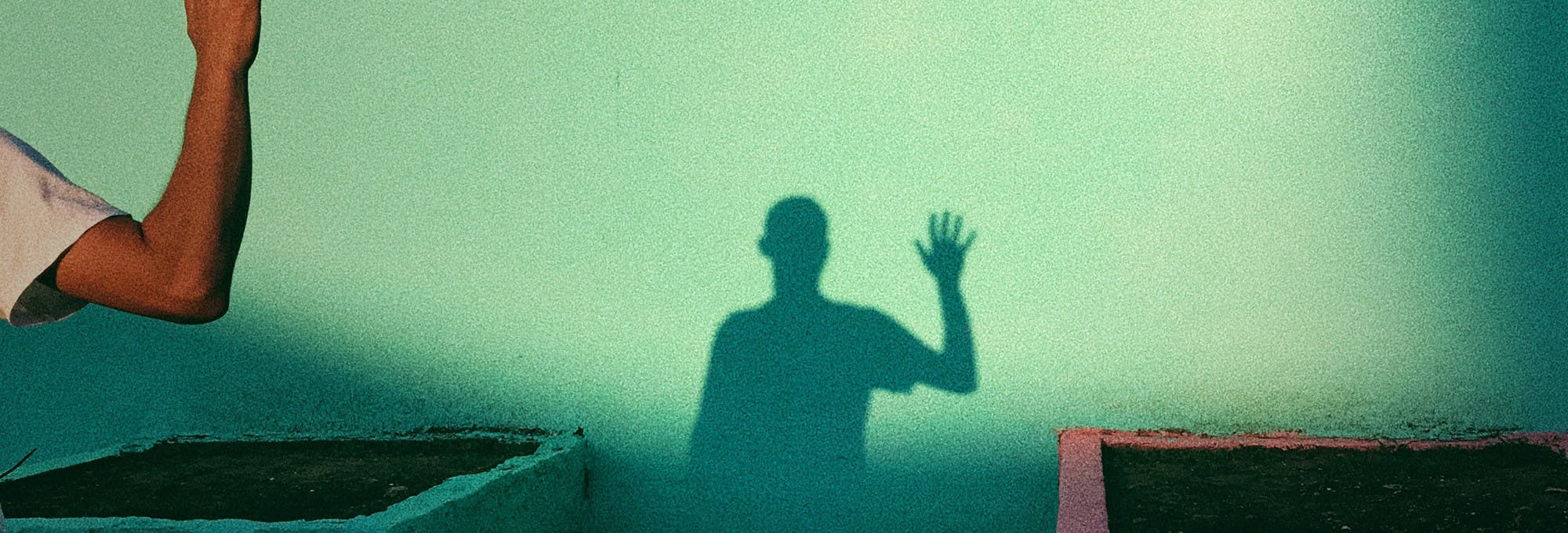 man holding up hand to wave and sees his shadow. This represents a handwave experiment with independent and dependent variables 