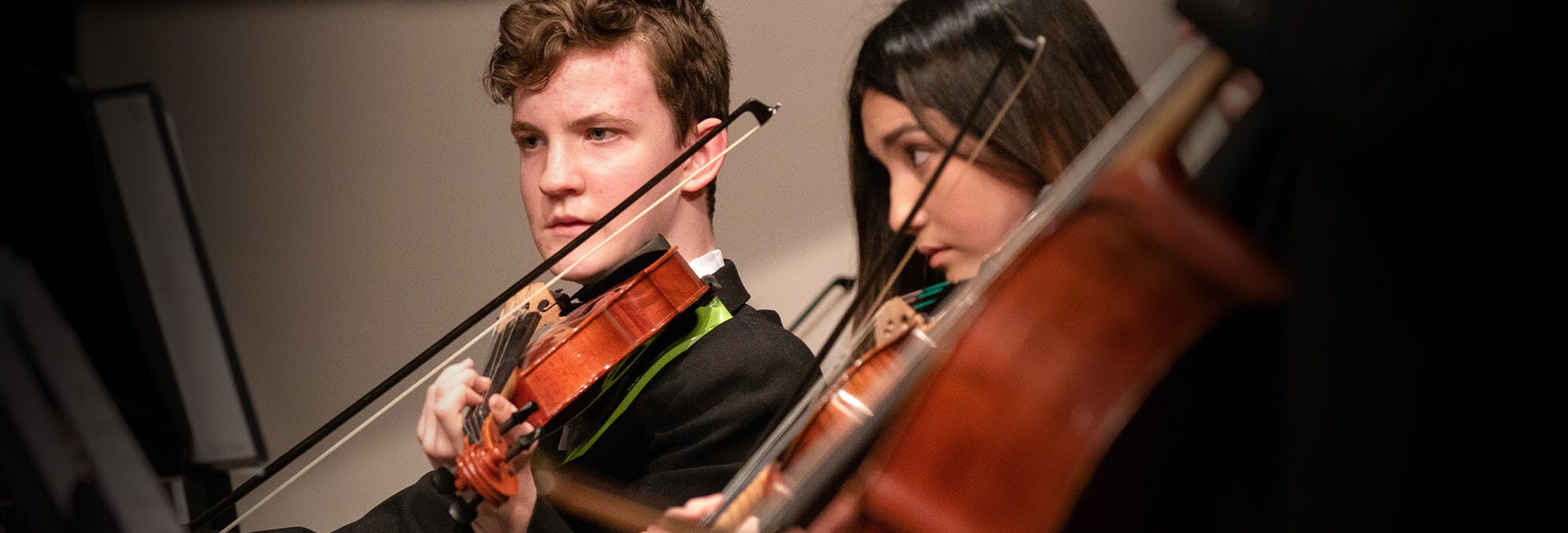  3 young adults playing strings for a symphony which helps represent musical intelligence