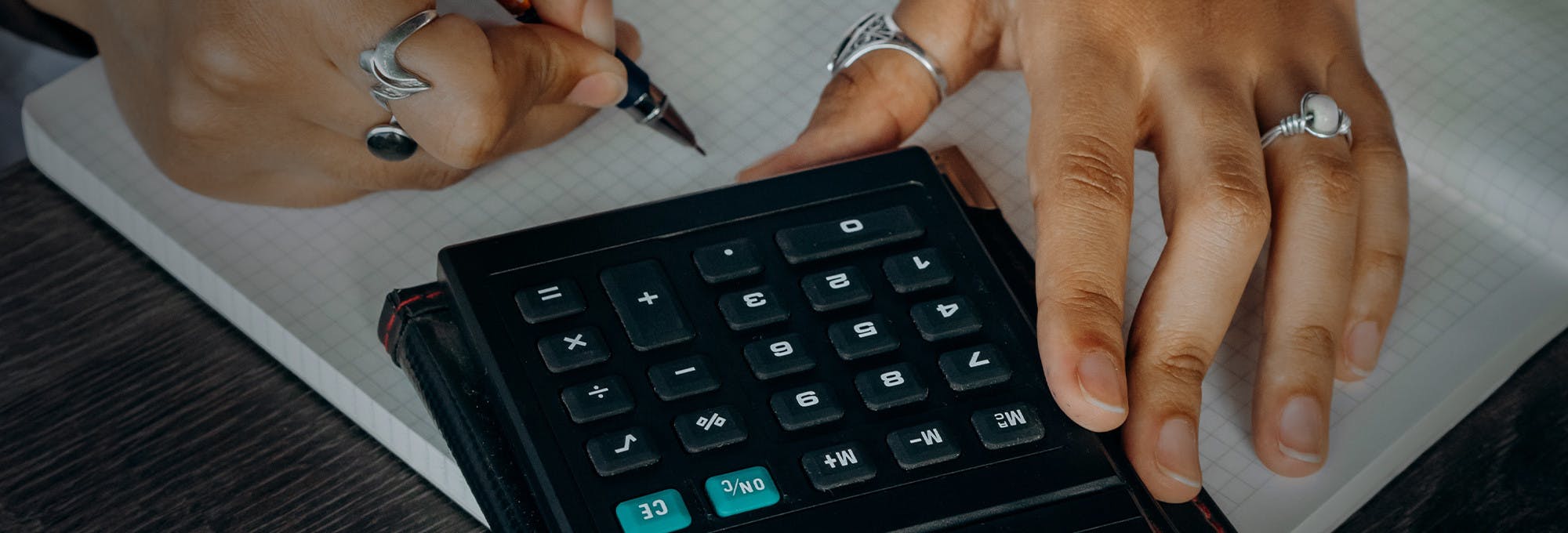 Hands using a calculator and paper to calculate student loans