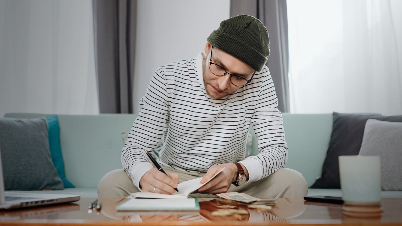 Male student with glasses on sitting and filling out application for a private student loan