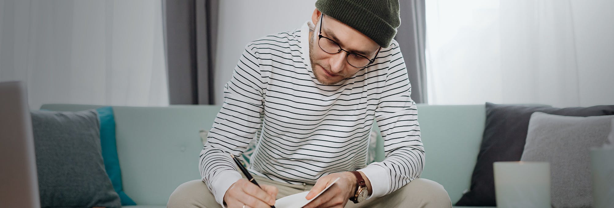 Male student with glasses on sitting and filling out application for a private student loan
