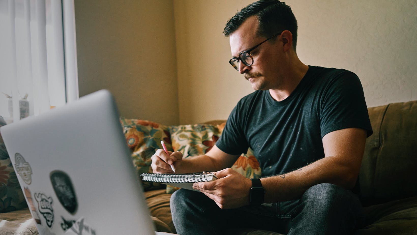Man at home on couch using his laptop to research career goals