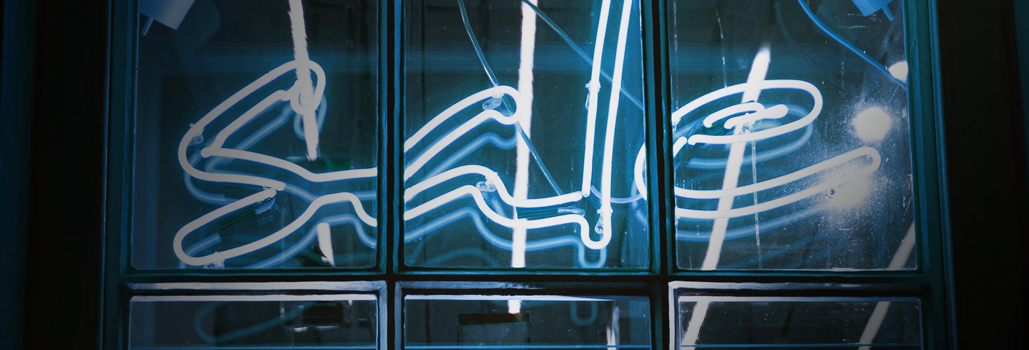 A blue and white neon "Sale" sign in a window.