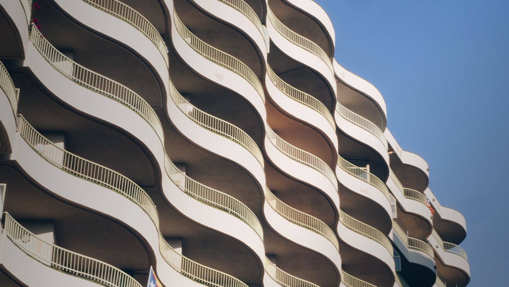 The side of a high rise building that has curving balconies which help represent concavity