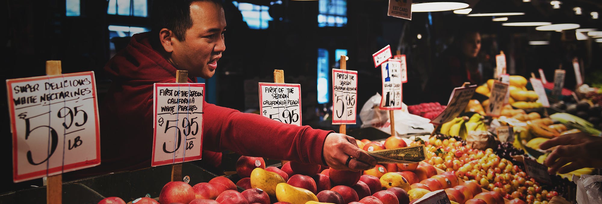A man at a fruit or farmers market making a purchase
