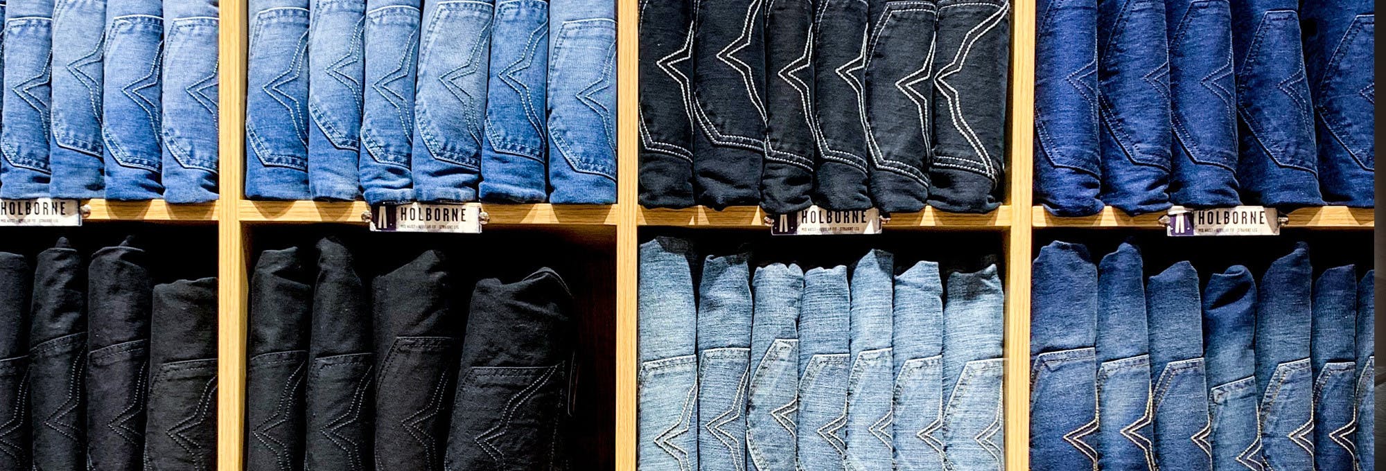 Stacks of different blue jeans in a shelf representing the topic elasticity of demand 
